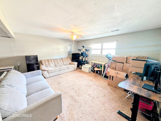 carpeted living room featuring ceiling fan and a textured ceiling