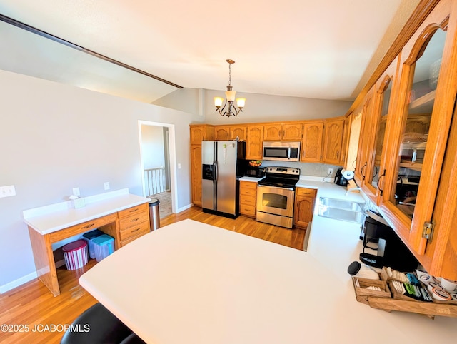 kitchen with sink, stainless steel appliances, a notable chandelier, decorative light fixtures, and vaulted ceiling