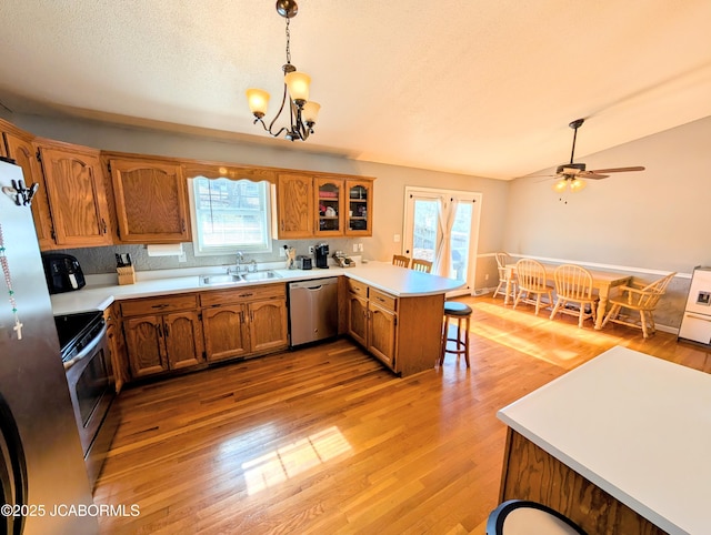 kitchen with sink, stainless steel appliances, a kitchen breakfast bar, decorative light fixtures, and kitchen peninsula