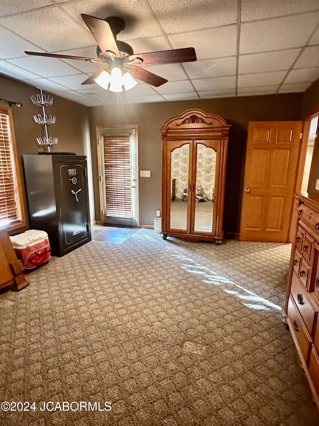 interior space featuring a paneled ceiling, ceiling fan, and carpet