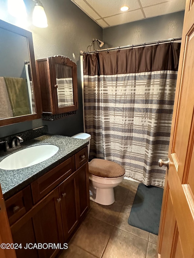 bathroom featuring tile patterned flooring, vanity, toilet, and a paneled ceiling