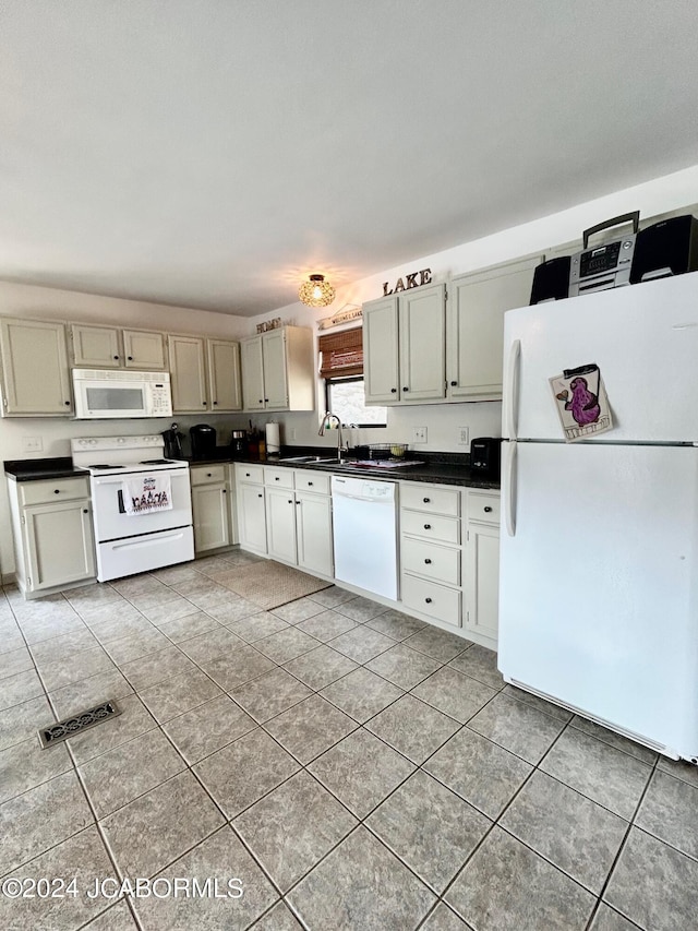 kitchen featuring light tile patterned flooring, white appliances, sink, and cream cabinetry