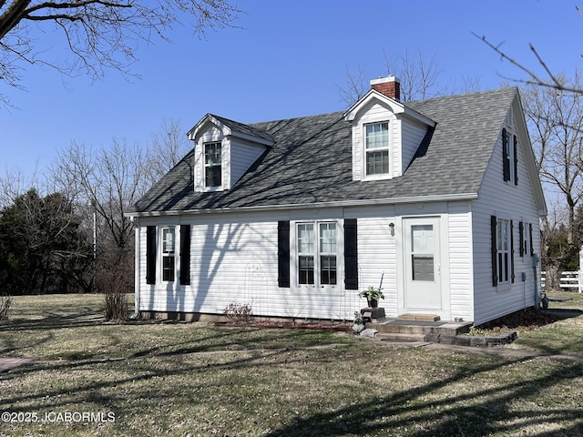 cape cod home featuring a chimney, roof with shingles, and a front yard