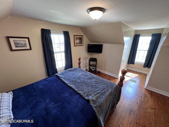 bedroom featuring lofted ceiling, hardwood / wood-style flooring, baseboards, and multiple windows