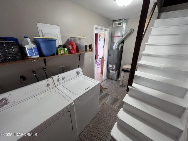 clothes washing area with washing machine and clothes dryer and wood finished floors
