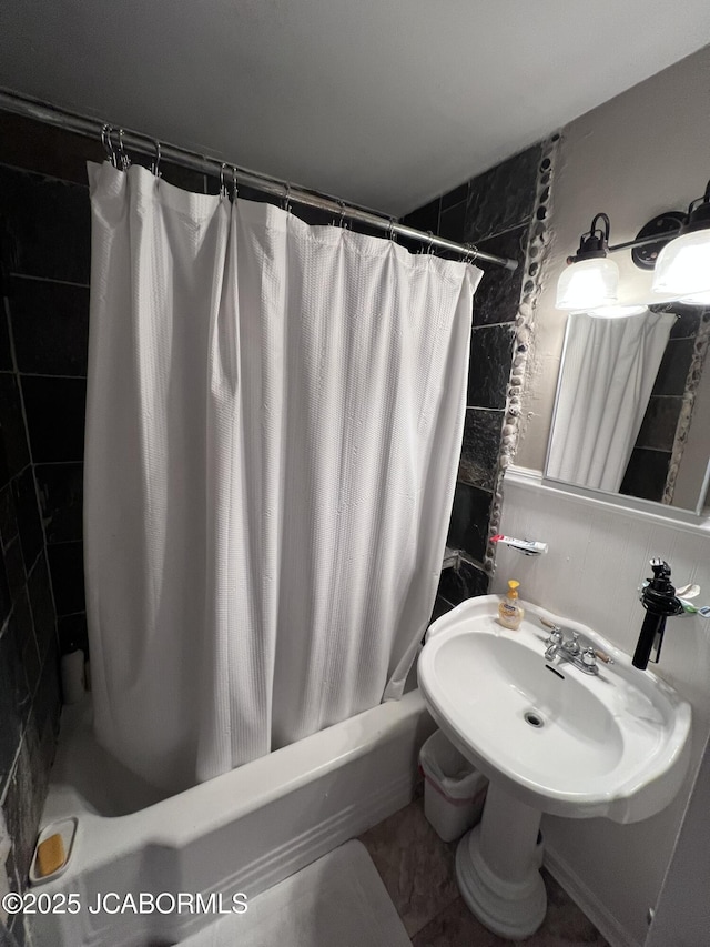 full bathroom featuring shower / bath combo with shower curtain, tile walls, and a sink