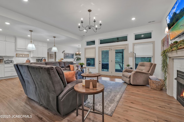 1308 Haxby Ct, Columbia, MO 65201 - living room with a lit fireplace, a chandelier, recessed lighting, and light wood-style floors