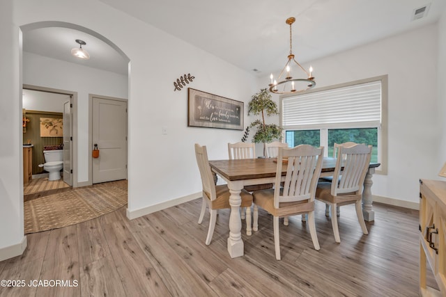 1308 Haxby Ct, Columbia, MO 65201 - dining room featuring arched walkways, a chandelier, light wood finished floors, and baseboards