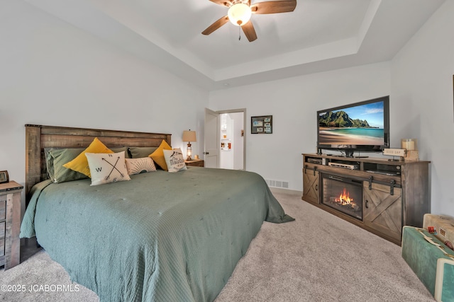 1308 Haxby Ct, Columbia, MO 65201 - bedroom with carpet floors, a glass covered fireplace, a raised ceiling, and ceiling fan