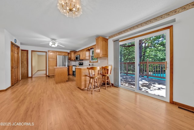 29311 State Highway Pp, California, MO 65018 - kitchen with stainless steel appliances, light wood-style flooring, a kitchen bar, light countertops, and a peninsula