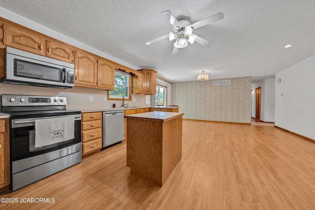 29311 State Highway Pp, California, MO 65018 - kitchen with stainless steel appliances, a center island, light countertops, light wood-type flooring, and wallpapered walls