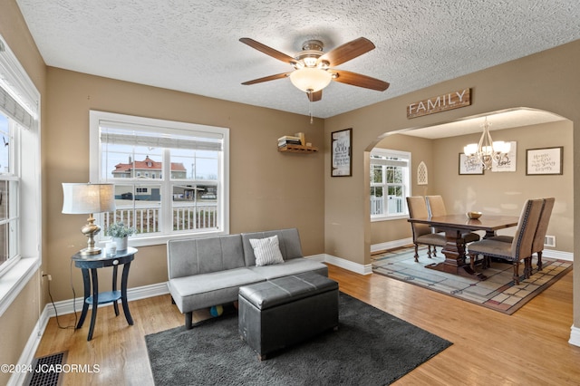 living room with hardwood / wood-style floors, ceiling fan with notable chandelier, and a textured ceiling