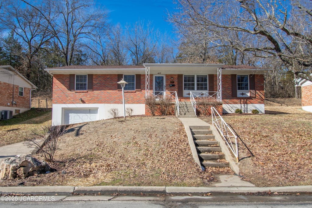 ranch-style home with a garage, stairs, cooling unit, a porch, and brick siding