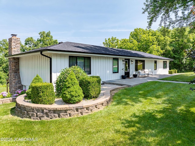 7165 E Hartman Rd, Hartsburg, MO 65039 - view of front of home with a chimney, a patio area, a front lawn, and board and batten siding