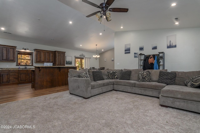 carpeted living room featuring lofted ceiling, sink, and ceiling fan with notable chandelier