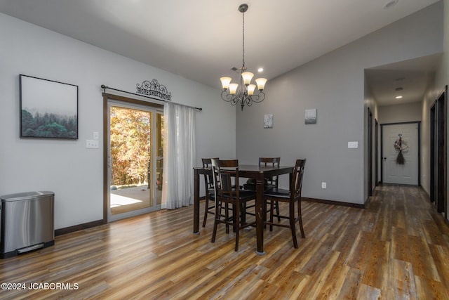 dining space with dark hardwood / wood-style flooring, lofted ceiling, and a chandelier