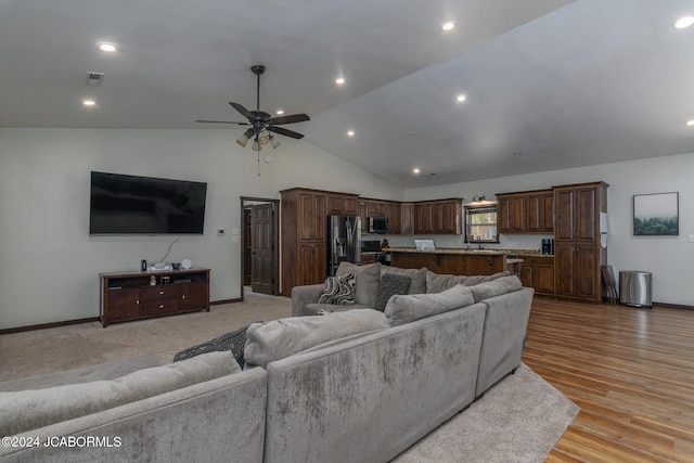 living room featuring light hardwood / wood-style flooring, vaulted ceiling, and ceiling fan