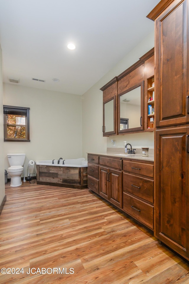 bathroom featuring a bathing tub, vanity, wood-type flooring, and toilet