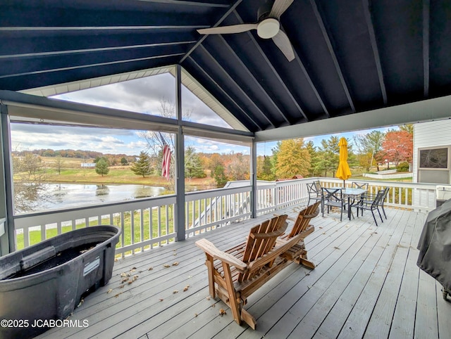 deck with a ceiling fan, outdoor dining space, and a water view