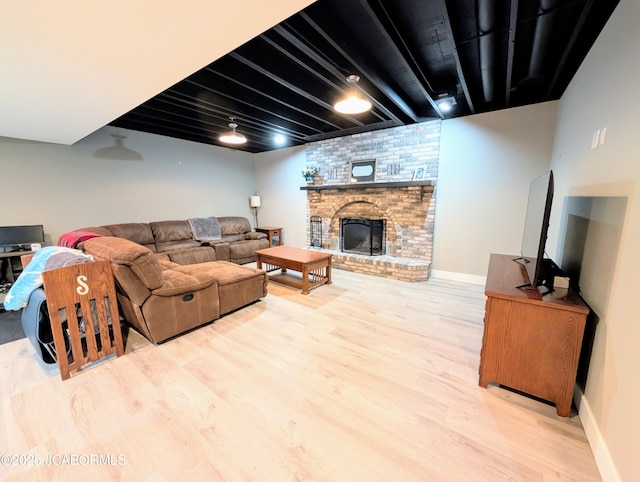 living area with a brick fireplace, baseboards, and wood finished floors