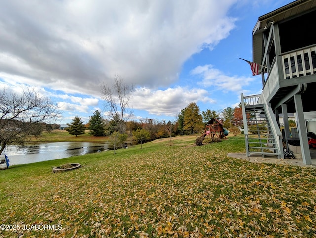 view of yard featuring a water view, playground community, and stairs