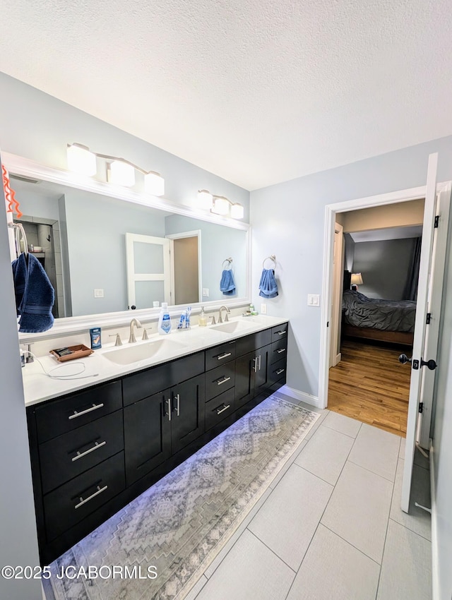 full bathroom with a sink, a textured ceiling, and double vanity