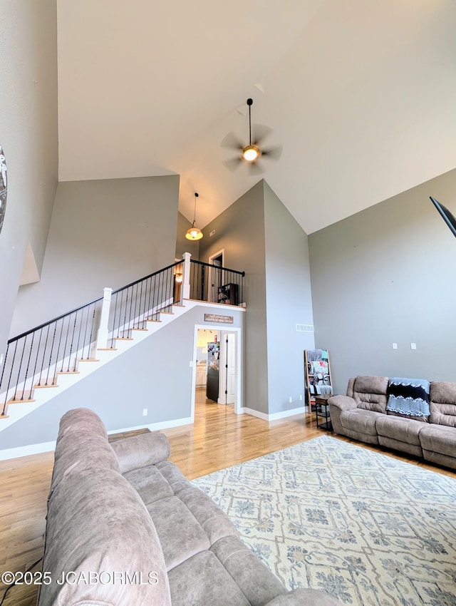 living room featuring high vaulted ceiling, ceiling fan, baseboards, and wood finished floors