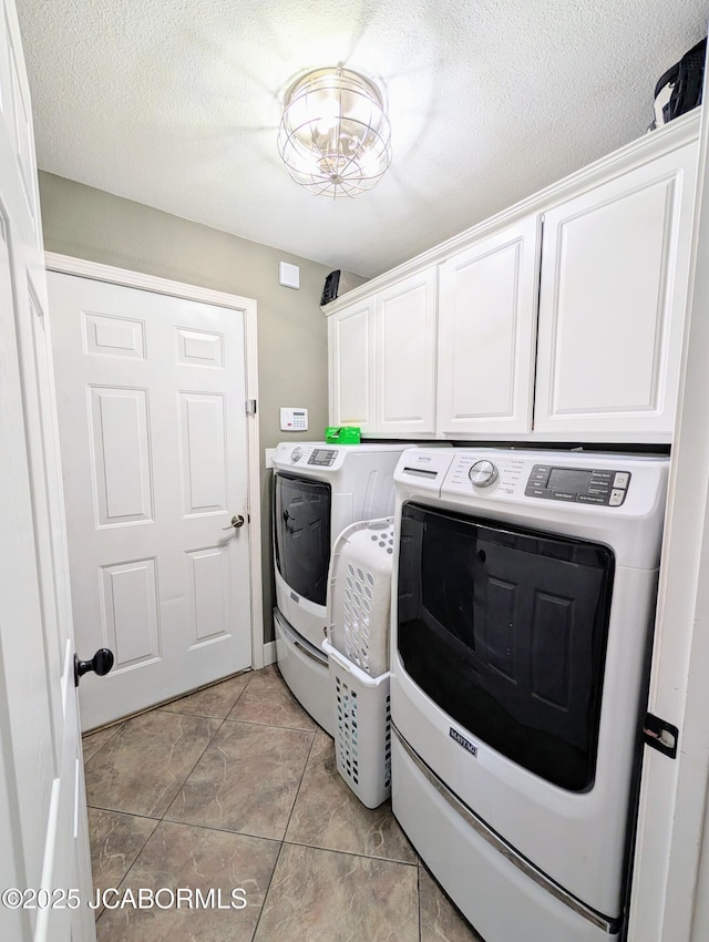 laundry area with cabinet space, a textured ceiling, and washer and dryer