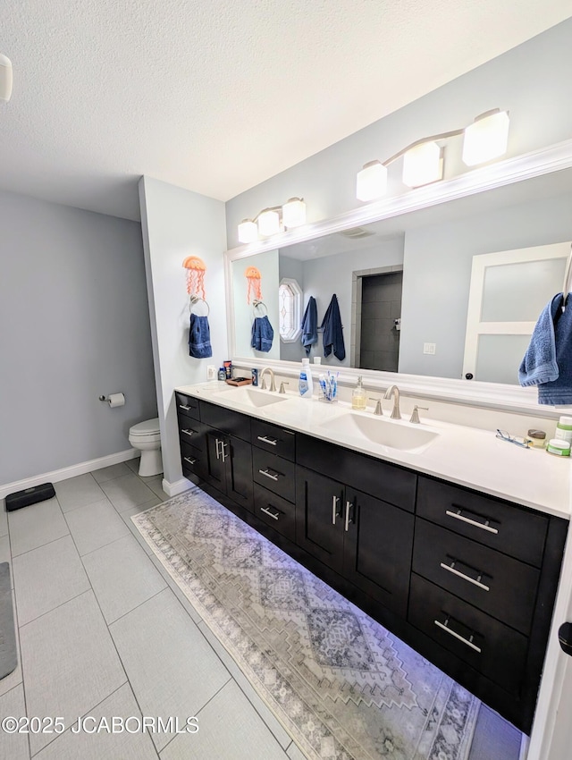 bathroom featuring double vanity, toilet, tile patterned flooring, a textured ceiling, and a sink