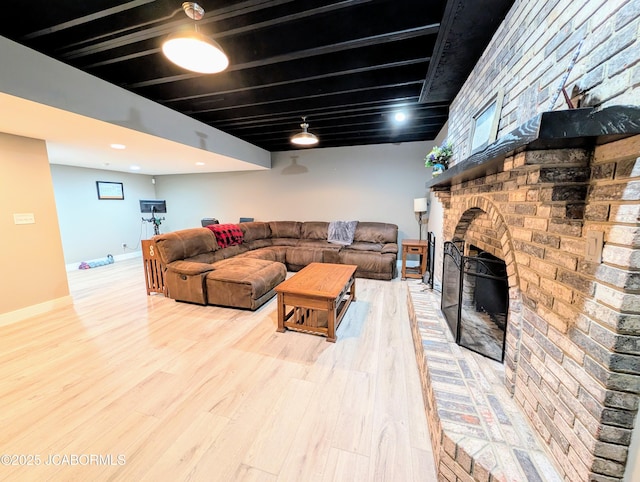 living room with a fireplace, baseboards, and wood finished floors