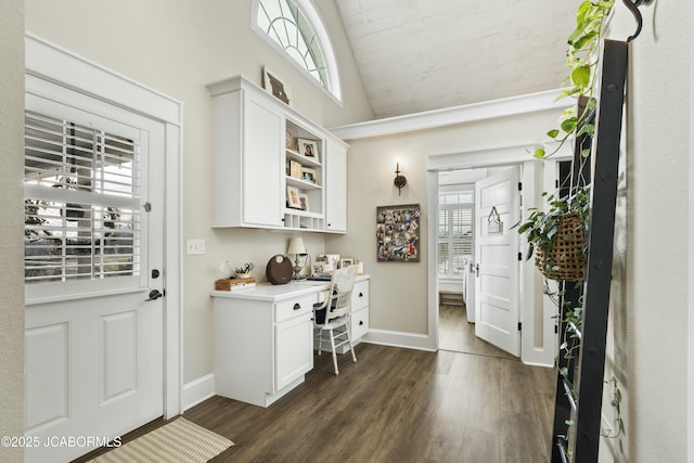 interior space with built in desk, dark hardwood / wood-style floors, and vaulted ceiling