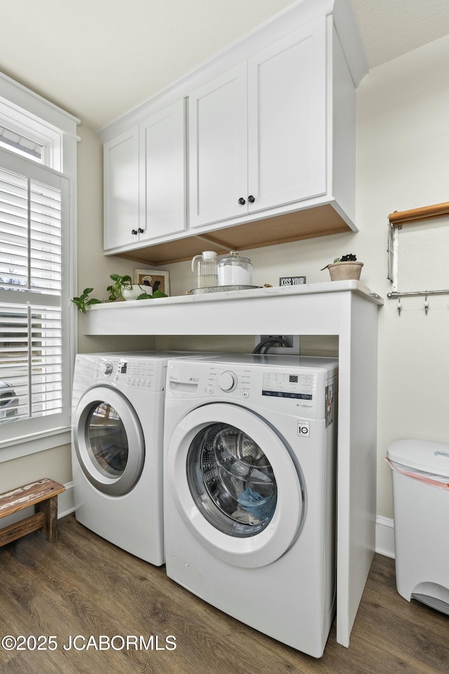 clothes washing area with cabinets, dark hardwood / wood-style flooring, and washing machine and clothes dryer