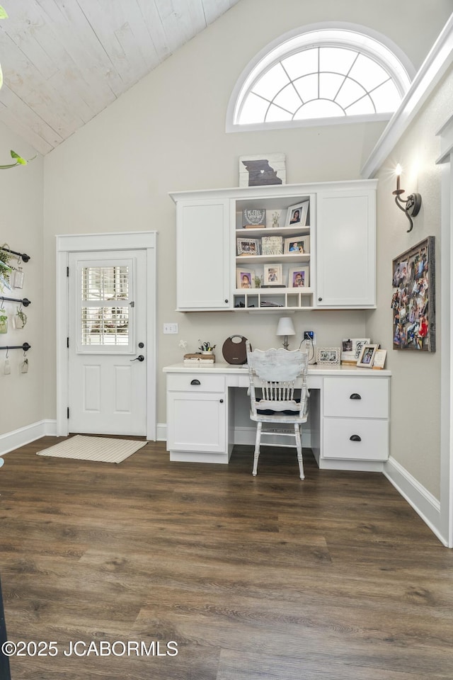 unfurnished office featuring dark hardwood / wood-style flooring, built in desk, and plenty of natural light