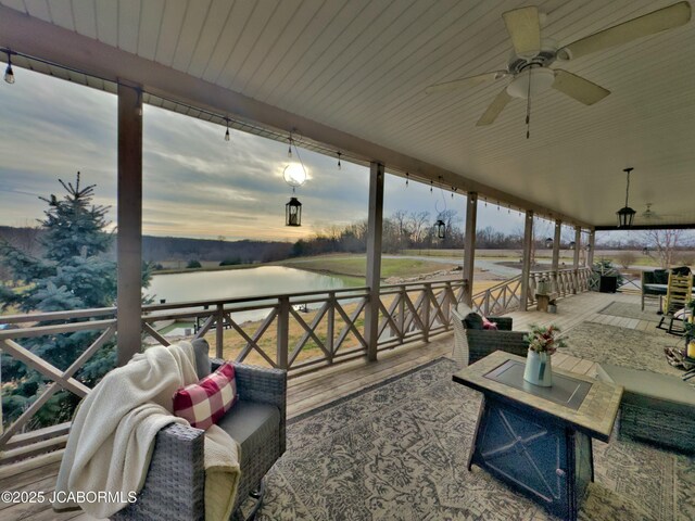 patio terrace at dusk featuring outdoor lounge area, a water view, and ceiling fan