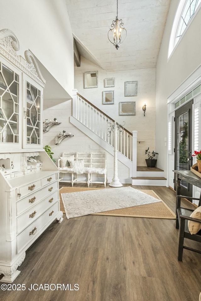 staircase featuring plenty of natural light, high vaulted ceiling, a chandelier, and hardwood / wood-style flooring