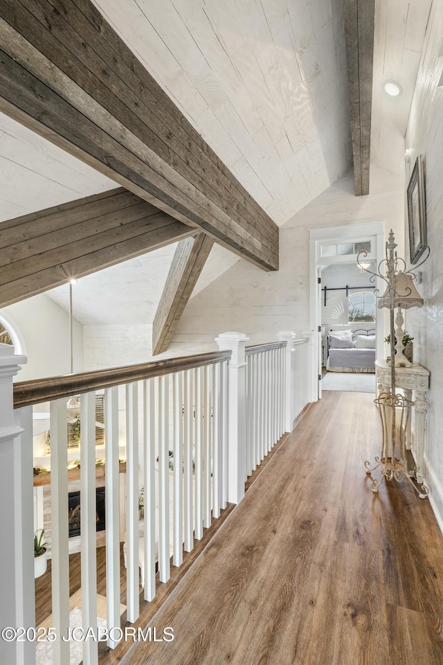 corridor with hardwood / wood-style flooring and vaulted ceiling with beams