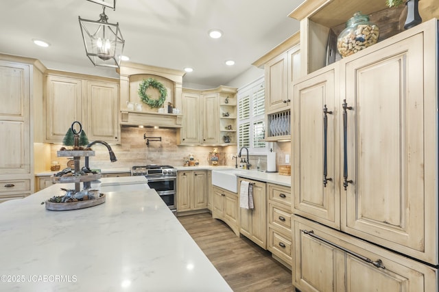 kitchen featuring light stone countertops, decorative backsplash, sink, range with two ovens, and hanging light fixtures