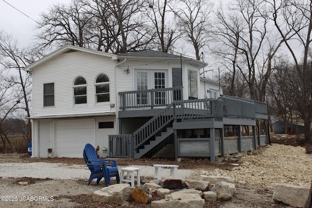 back of property with an attached garage, stairs, and a deck