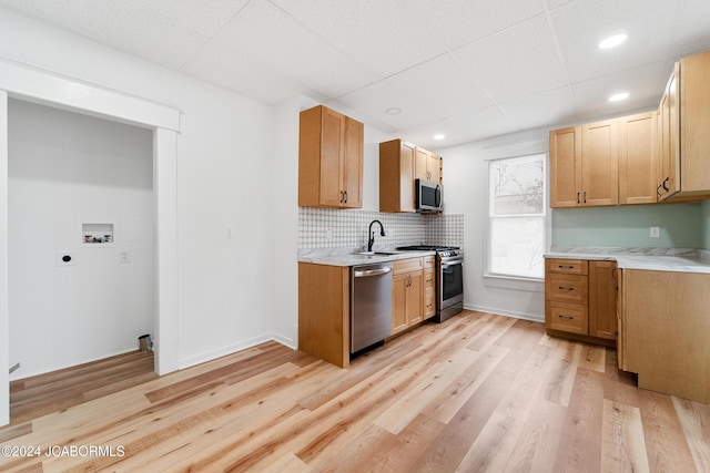 kitchen featuring light hardwood / wood-style floors, sink, stainless steel appliances, and tasteful backsplash