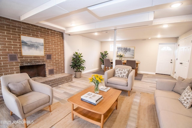 living room with visible vents, a fireplace, light wood-style flooring, and baseboards