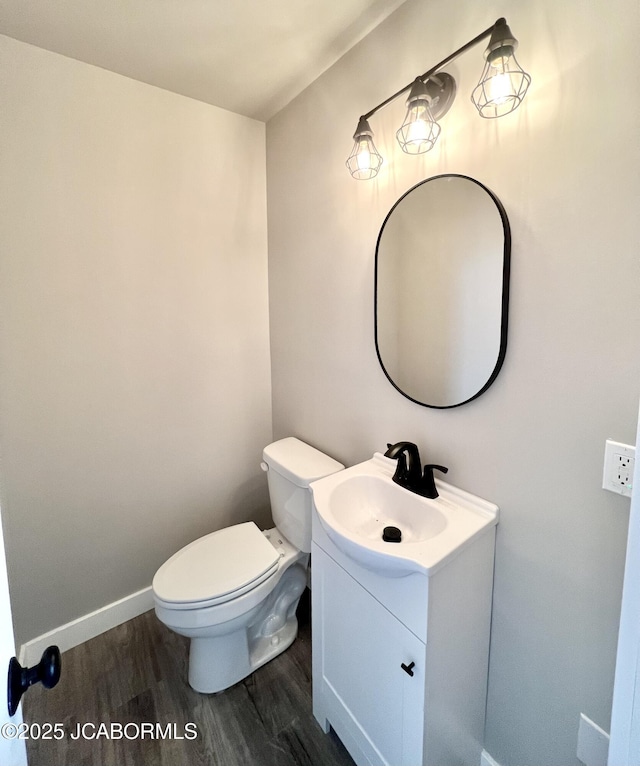 half bath featuring toilet, baseboards, wood finished floors, and vanity