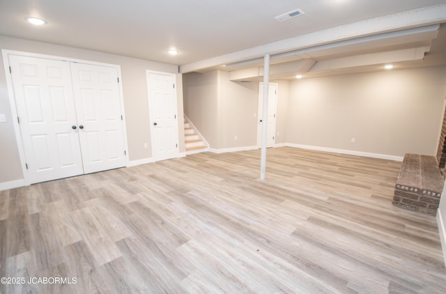 finished below grade area featuring visible vents, baseboards, light wood-style flooring, stairs, and recessed lighting