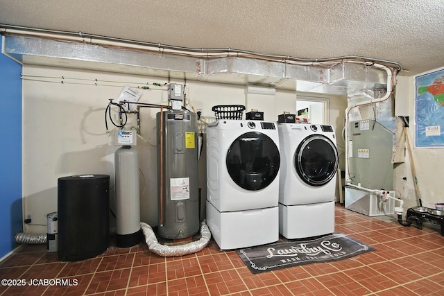 washroom featuring electric water heater, a textured ceiling, and washing machine and clothes dryer