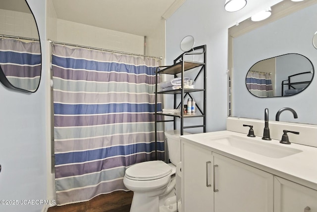 bathroom featuring wood-type flooring, crown molding, vanity, and toilet