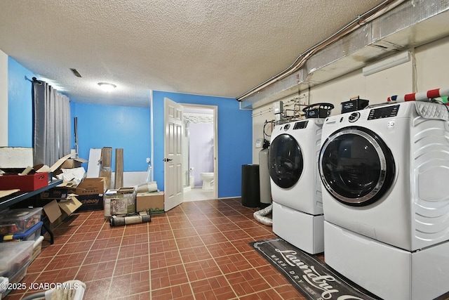 washroom featuring a textured ceiling and washer and clothes dryer