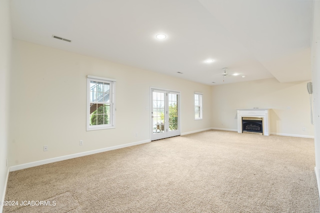 unfurnished living room featuring light carpet, french doors, and ceiling fan