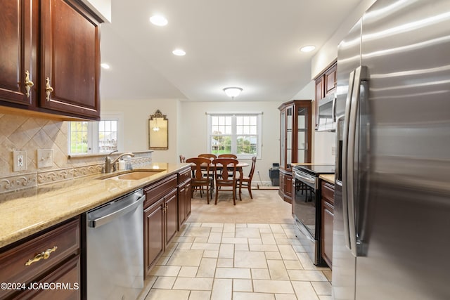 kitchen featuring decorative backsplash, appliances with stainless steel finishes, light stone counters, and sink