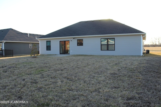 rear view of house featuring a yard and roof with shingles