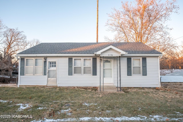 ranch-style home with a front lawn and roof with shingles