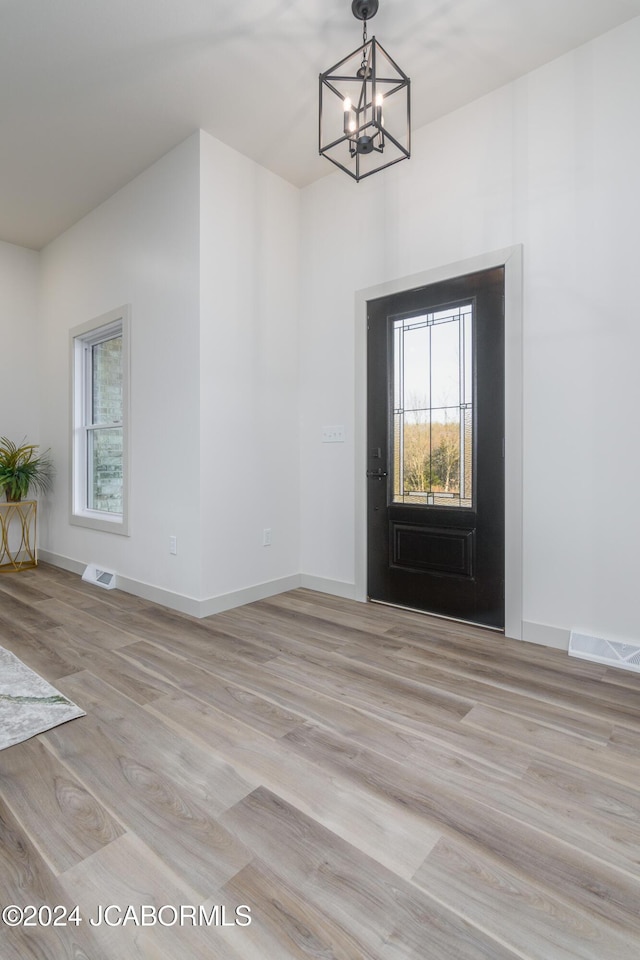 foyer entrance with light hardwood / wood-style flooring and a notable chandelier